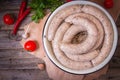 Raw fresh white sausages on a plate with vegetables. Weisswurst in a heap. Traditional Bavarian or Munich white sausage made from Royalty Free Stock Photo