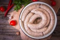 Raw fresh white sausages on a plate with vegetables. Weisswurst in a heap. Traditional Bavarian or Munich white sausage made from Royalty Free Stock Photo