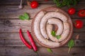 Raw fresh white sausages on a plate with vegetables. Weisswurst in a heap. Traditional Bavarian or Munich white sausage made from