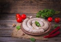 Raw fresh white sausages on a plate with vegetables. Weisswurst in a heap. Traditional Bavarian or Munich white sausage made from