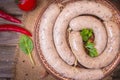 Raw fresh white sausages on a plate with vegetables. Weisswurst in a heap. Traditional Bavarian or Munich white sausage made from