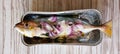 The raw freshwater mackerel fish 'scomber scombrus' with slices of onion in almunium foil