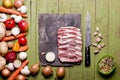 Raw frozen meat on green wooden background. Pork neck raw, vegetables close-up on a slate board. Copy space