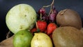 Raw fruits and berries in rainbow colours, strawberries, mango, grapes, grapefruit, kiwi, limes, lemon on the off wood table