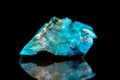 Raw gemstone in front of black, blue Chrysocolla mineral stone