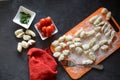 Raw Gnocchi, tomatoes, bowls, fork on dark table, in the kitchen