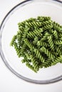 Raw green fusilli pasta in a transparent plate, natural based on spinach and spirulina. Delicious and healthy food. Close-up