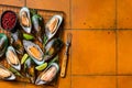 Raw green kiwi mussels in shells with herbs. Orange background. Top view. Copy space