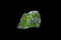 Raw Peridot. Green uncut stone on black background.