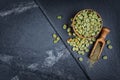 Raw green unroasted coffee in wooden bowl with ground beans in wood scoop on black slate board Royalty Free Stock Photo