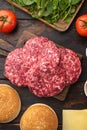 Raw Ground beef meat Burger steak cutlets with ingredients and buns, on old dark  wooden table background, top view flat lay Royalty Free Stock Photo