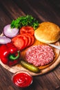 Raw Ground beef meat Burger steak cutlets with seasoning, cheese, tomatoes, salad and bun on vintage wooden boards Royalty Free Stock Photo