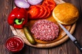 Raw Ground beef meat Burger steak cutlets with seasoning, cheese, tomatoes, salad and bun on vintage wooden boards Royalty Free Stock Photo