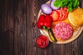 Raw Ground beef meat Burger steak cutlets with seasoning, cheese, tomatoes, salad and bun on vintage wooden boards Royalty Free Stock Photo