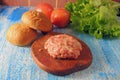 Raw Ground beef meat Burger steak cutlets with seasoning, cheese, tomatoes, salad and bun on vintage wooden boards, black Royalty Free Stock Photo