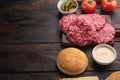 Raw Ground beef meat Burger steak cutlets and seasonings with buns, on old dark  wooden table background, with copy space for text Royalty Free Stock Photo