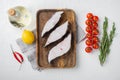 Raw halibut, with ingredients and rosemary herbs, on white stone table background, top view flat lay