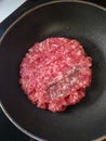 Raw hamburger being cooked in a frying pan
