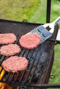 Raw hamburger slices cooking on grill with flames