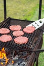 Raw hamburger slices cooking on grill with flames