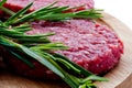 Raw hamburgers with cellophane and rosemary on wooden board Royalty Free Stock Photo