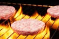 Raw hamburgers on grill with flame Royalty Free Stock Photo