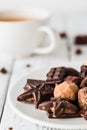 Raw handmade chocolate candies, cup of tea on white wooden background