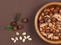 Raw hazelnuts in a bowl, macadamia and pistachio on brown suede background