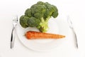 Raw head of broccoli and carrots on a plate on the table on a white background. Veganism and raw food. Healthy eating Close-up