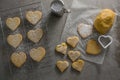 Raw heart shape cookies on baking tray with flour shaker strainer, cookie cutter and wax paper Royalty Free Stock Photo
