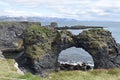 Hiking trail from Anarstapi to Hellnar with the raw ocean und big rocks and mountains and a stone gate in the west of Iceland at S