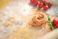 Raw homemade colored spaghetti nest with flour on a wooden table