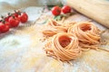 Raw homemade colored spaghetti nest with flour on a wooden table