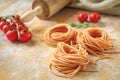 Raw homemade colored spaghetti nest with flour on a wooden table