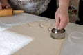 The raw homemade dough for the donuts is being cut into round pieces with the help of a rolling pin on the baking table Royalty Free Stock Photo