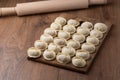Raw homemade dumplings with minced meat on wooden board on table with rolling pin, sprinkled with flour. Close up view Royalty Free Stock Photo