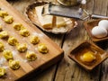 Raw homemade dumplings on a wooden cutting board are waiting to be cooked. Kitchen utensils and ingredients on a simple wooden