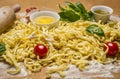 Raw homemade pasta with fresh herbs , tomatoes, flour, rolling pin ,egg and olive oil on rustic wooden background close up Royalty Free Stock Photo