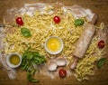 Raw homemade pasta with ingredients for pasta, tomatoes, flour, rolling pin ,egg and olive oil on rustic wooden background top vi Royalty Free Stock Photo