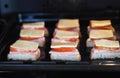 Raw homemade sandwiches with sausage, tomatoes and cheese on a baking sheet in the kitchen oven, cooked for frying. Natural