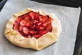 Raw homemade strawberry galette pie on baking sheet on white table. Top view Royalty Free Stock Photo