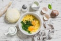 Raw ingredients for baking a pie with spinach - eggs, cheese, dough, spinach, cream on light wooden background.