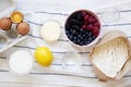 Raw ingredients: berries, flour, eggs, butter, lemon, water, sugar, salt for cooking berry pie on white wooden background, top vie Royalty Free Stock Photo