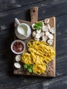 Raw ingredients for cooking pasta with mushroom cream sauce - pasta, mushrooms, cream, spices. On rustic wooden board Royalty Free Stock Photo