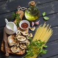 Raw ingredients for cooking pasta with porcini - dried porcini mushrooms, spaghetti, cream, garlic, parsley, basil, olive oil and Royalty Free Stock Photo