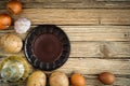 Raw ingredients for cooking potato pancakes around an empty plate on an old wooden background. potatoes, eggs, onions, garlic and