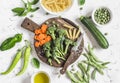 Raw ingredients for cooking vegetarian lunch - dry pasta, fresh broccoli, zucchini, green peas and beans, carrots, olive oil. Royalty Free Stock Photo