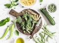 Raw ingredients for cooking vegetarian lunch - dry pasta, fresh broccoli, zucchini, green peas and beans, olive oil. Royalty Free Stock Photo