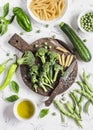 Raw ingredients for cooking vegetarian lunch - dry pasta, fresh broccoli, zucchini, green peas and beans, olive oil. Royalty Free Stock Photo