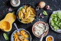 Raw ingredients for making pumpkin and ricotta stuffed shells. Pasta shells, pumpkin, spinach, ricotta. On a dark background, top